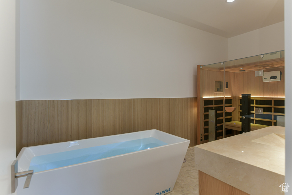 Bathroom featuring tile flooring, wood walls, and a bathtub