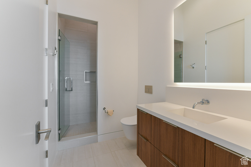 Bathroom featuring tile floors, vanity, toilet, and a shower with door