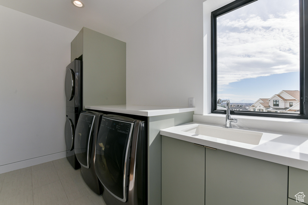 Laundry room featuring sink, light tile flooring, a wealth of natural light, and cabinets