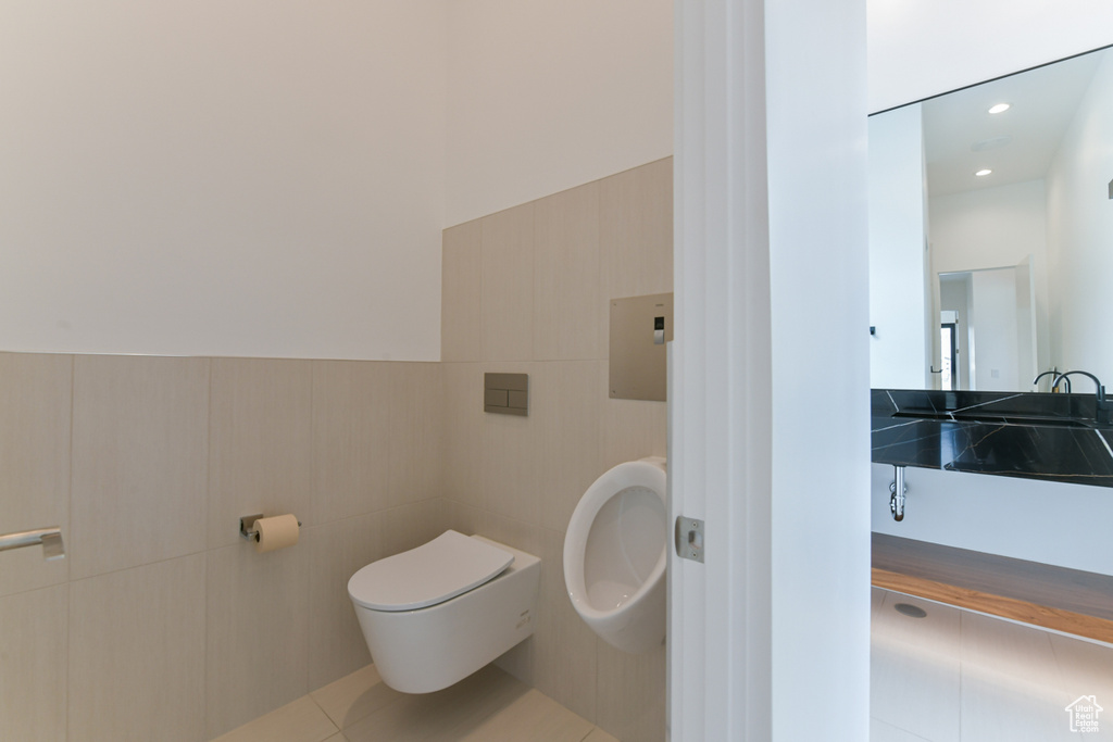 Bathroom featuring sink, tile floors, tile walls, and toilet