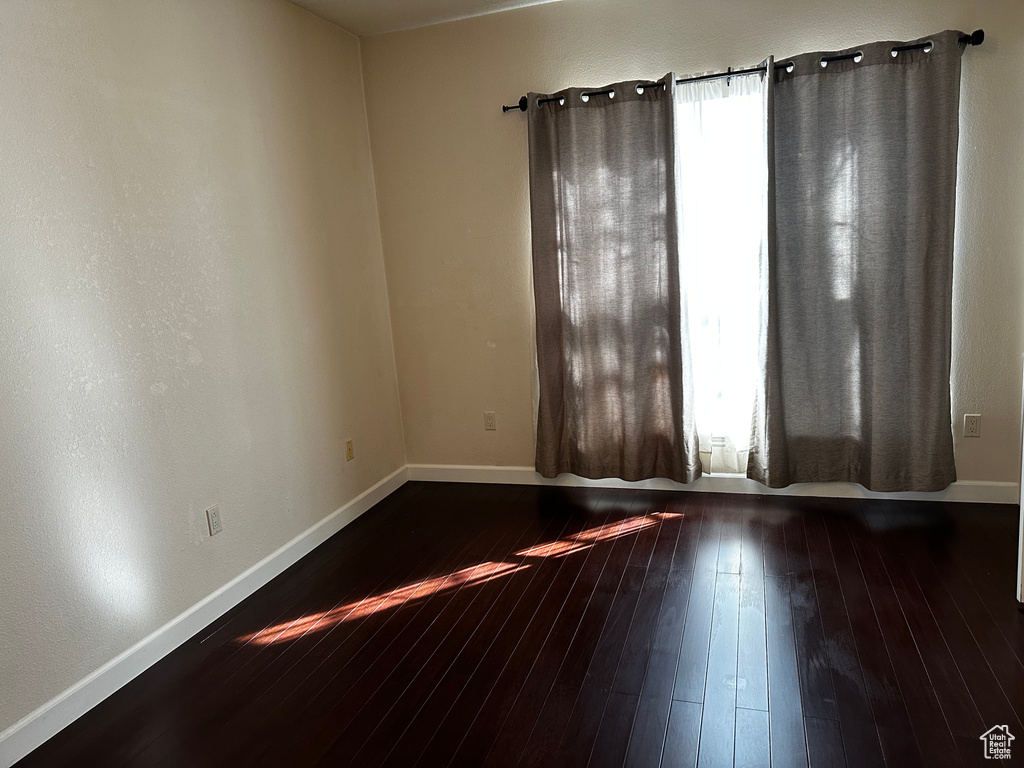 Empty room featuring plenty of natural light and dark hardwood / wood-style flooring