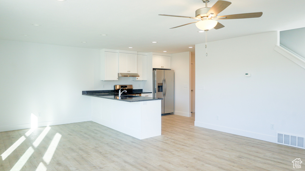 Kitchen with white cabinets, kitchen peninsula, stainless steel fridge, light wood-type flooring, and ceiling fan