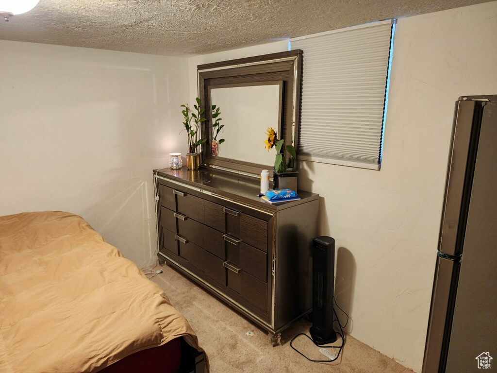 Carpeted bedroom with stainless steel refrigerator and a textured ceiling
