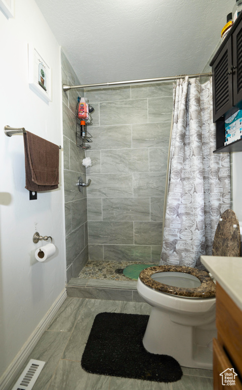 Bathroom with vanity, toilet, tile floors, and a shower with curtain