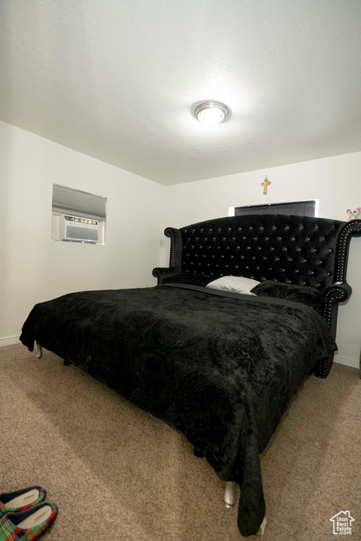 Bedroom with a wall mounted AC and carpet flooring