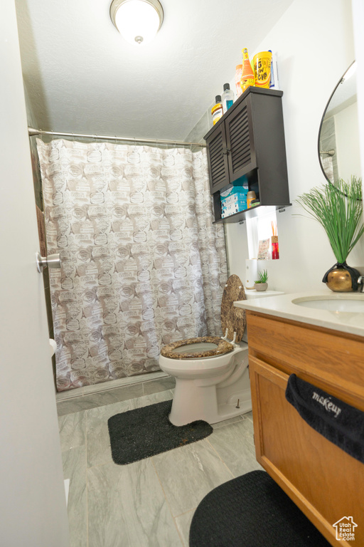 Bathroom featuring vanity, toilet, and tile flooring