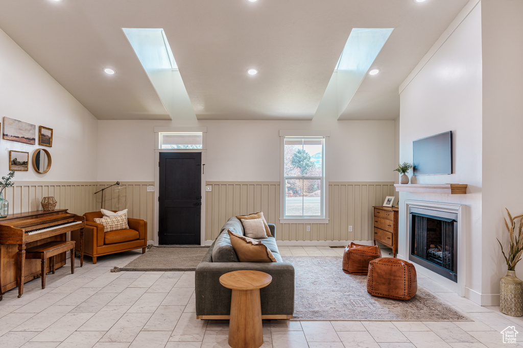 Living room featuring lofted ceiling with skylight and light tile floors