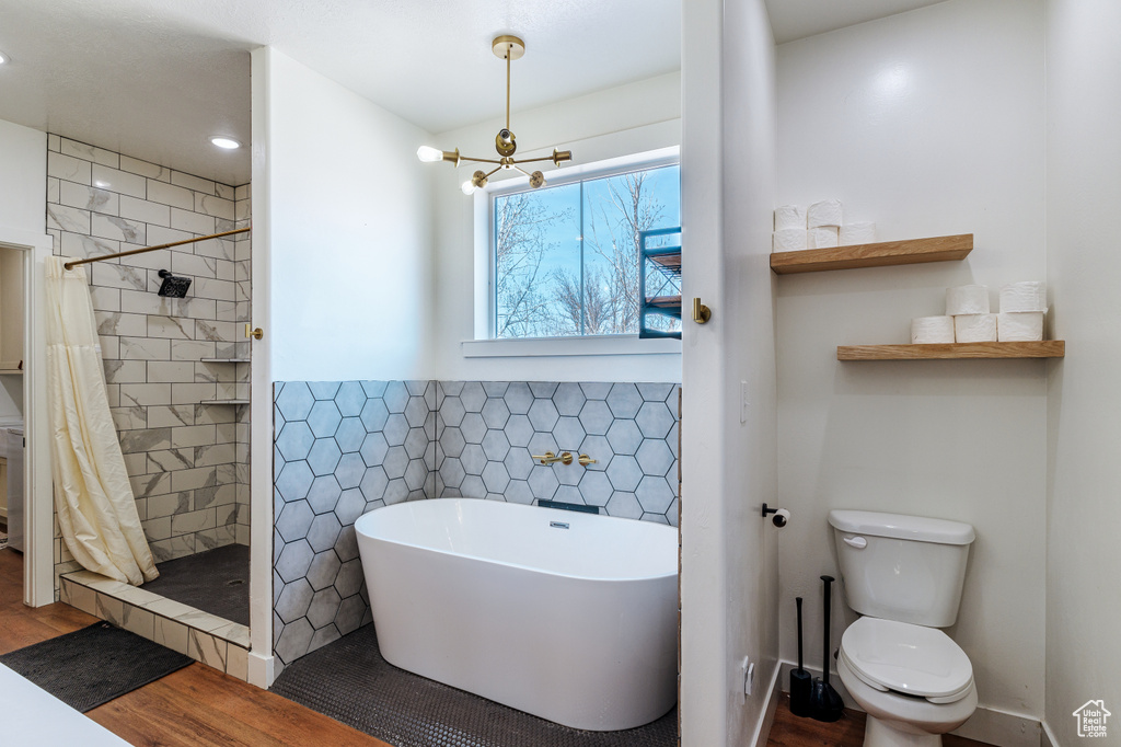 Bathroom featuring a shower with shower curtain, hardwood / wood-style floors, toilet, and a chandelier