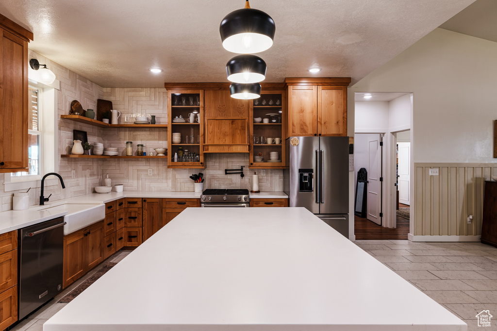 Kitchen with sink, backsplash, stainless steel appliances, and light tile flooring