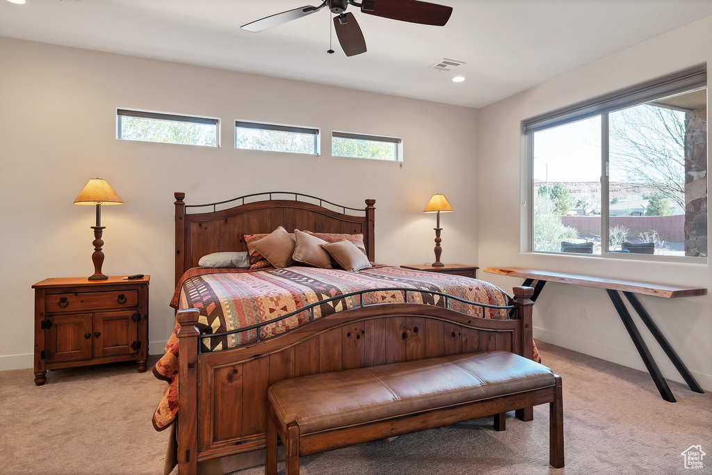 Bedroom with light carpet, multiple windows, and ceiling fan