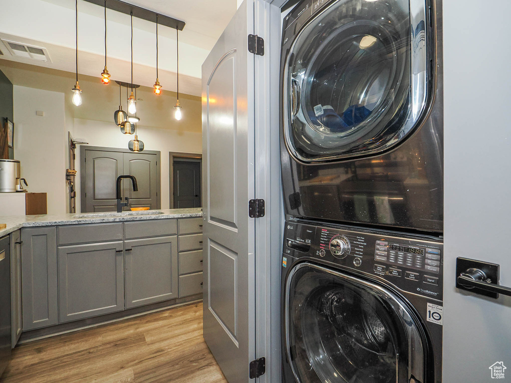 Laundry area featuring sink, light hardwood / wood-style floors, and stacked washer and dryer