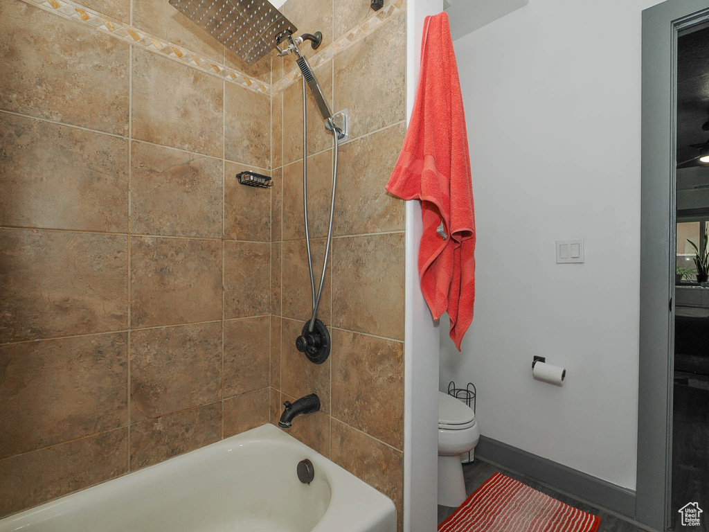 Bathroom featuring tiled shower / bath combo and toilet