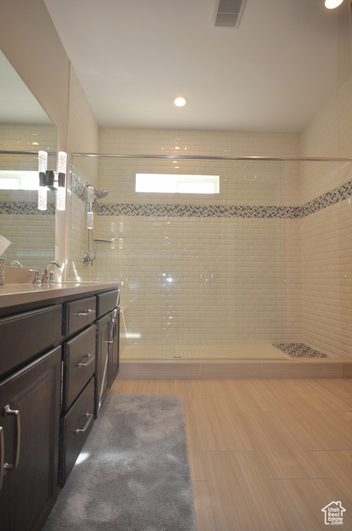 Bathroom with tile floors, vanity, and tiled shower