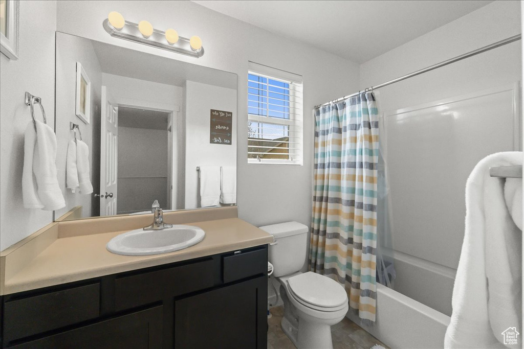Full bathroom with tile floors, shower / bath combo with shower curtain, toilet, and vanity