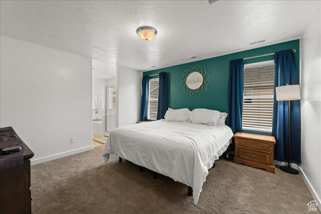 Bedroom with dark carpet, connected bathroom, and a textured ceiling