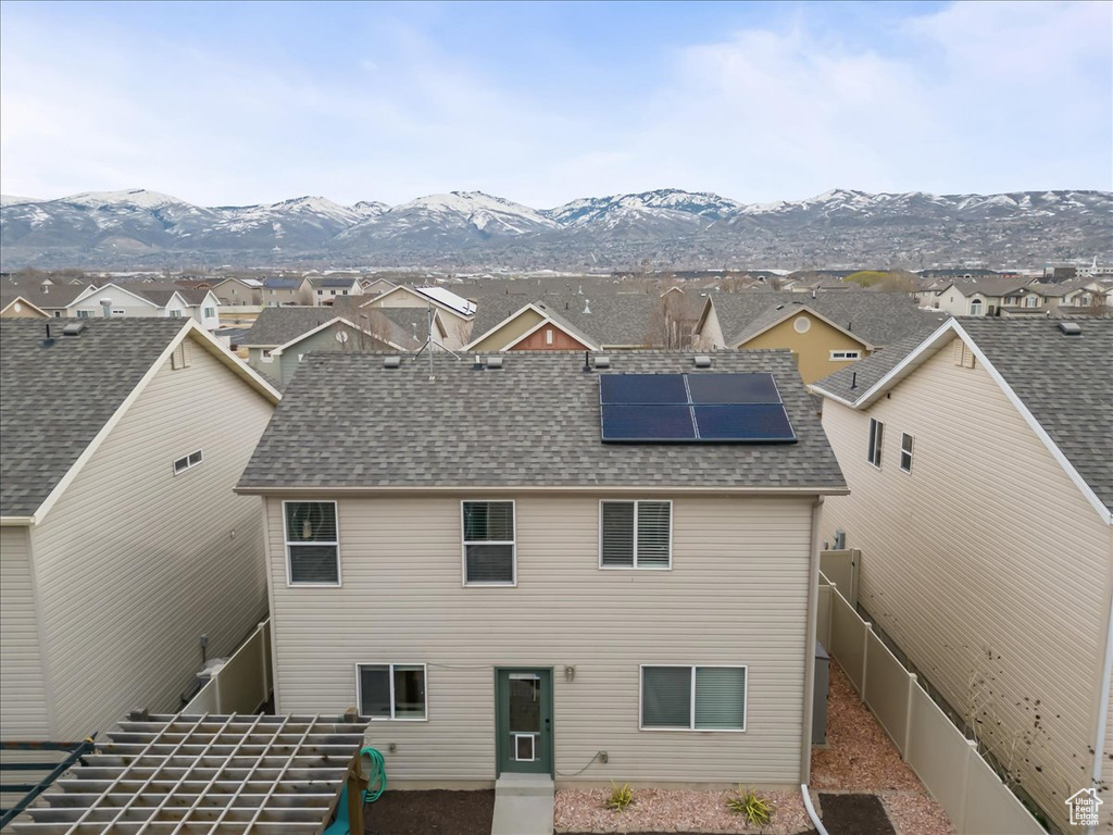 Rear view of property featuring a mountain view and solar panels