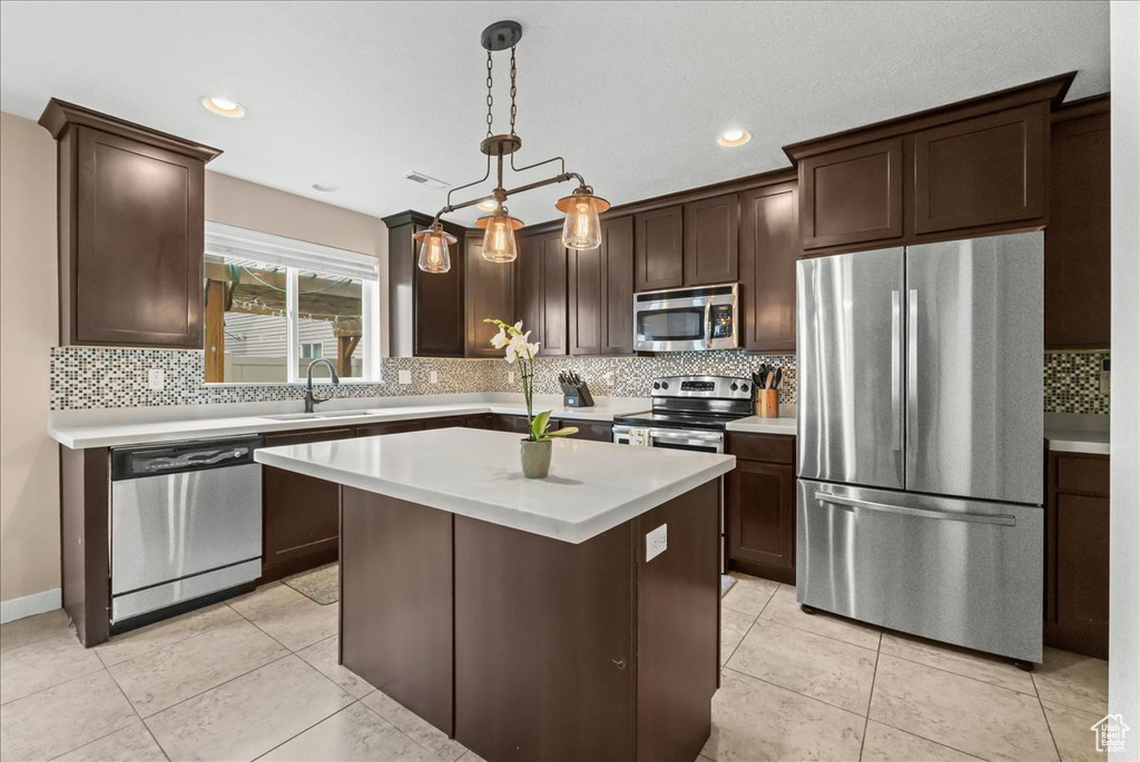 Kitchen featuring a center island, sink, hanging light fixtures, backsplash, and stainless steel appliances
