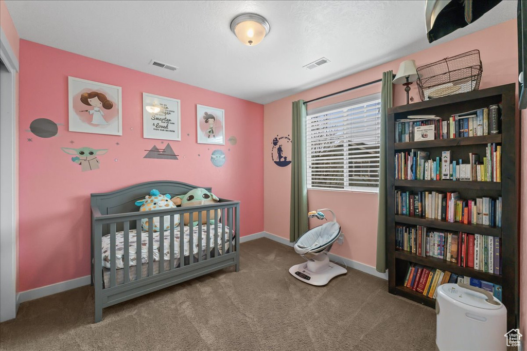 Bedroom with a crib and dark carpet