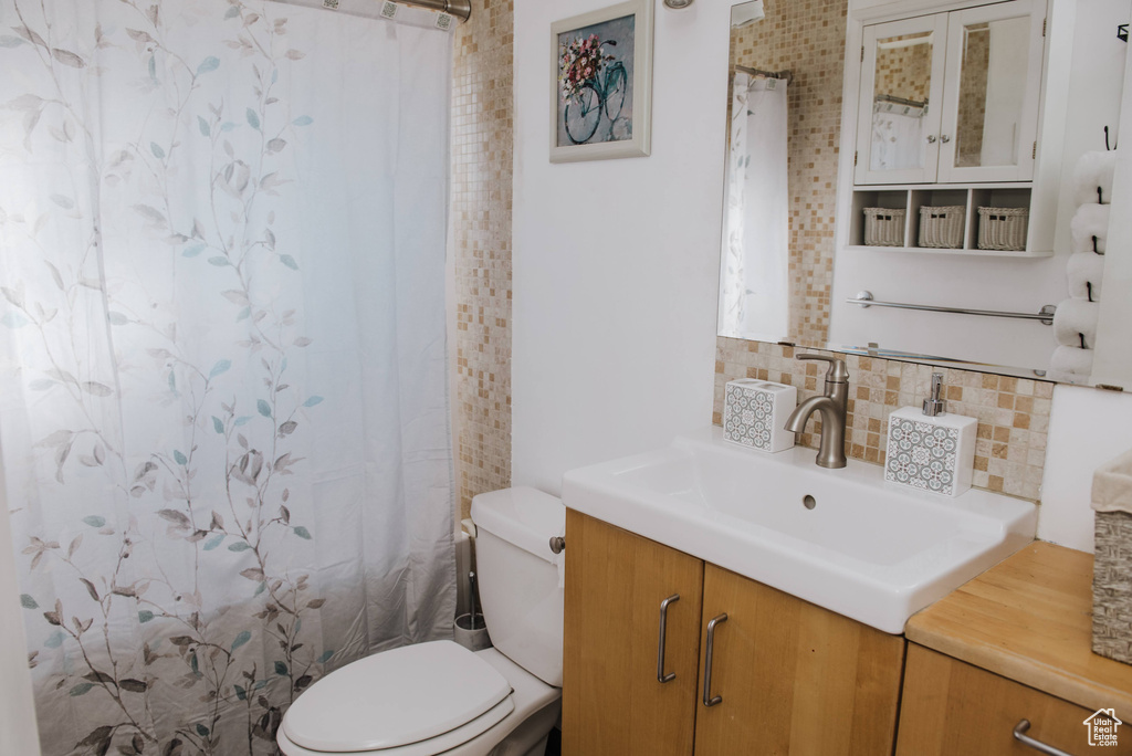Bathroom featuring backsplash, toilet, and vanity