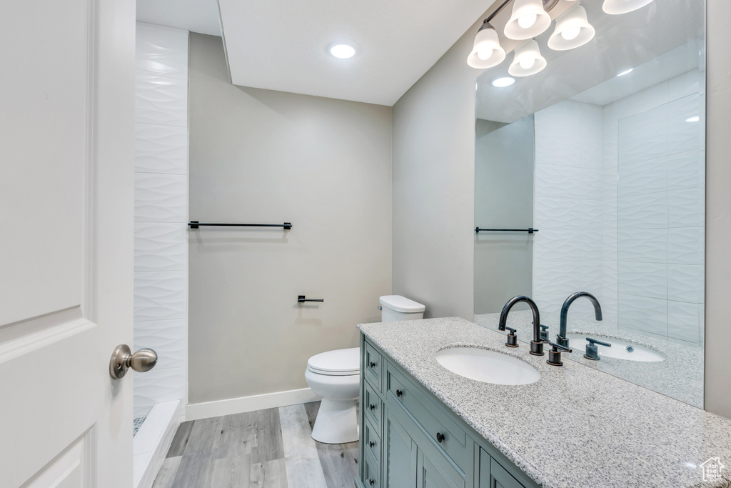 Bathroom featuring vanity, toilet, a tile shower, and hardwood / wood-style floors