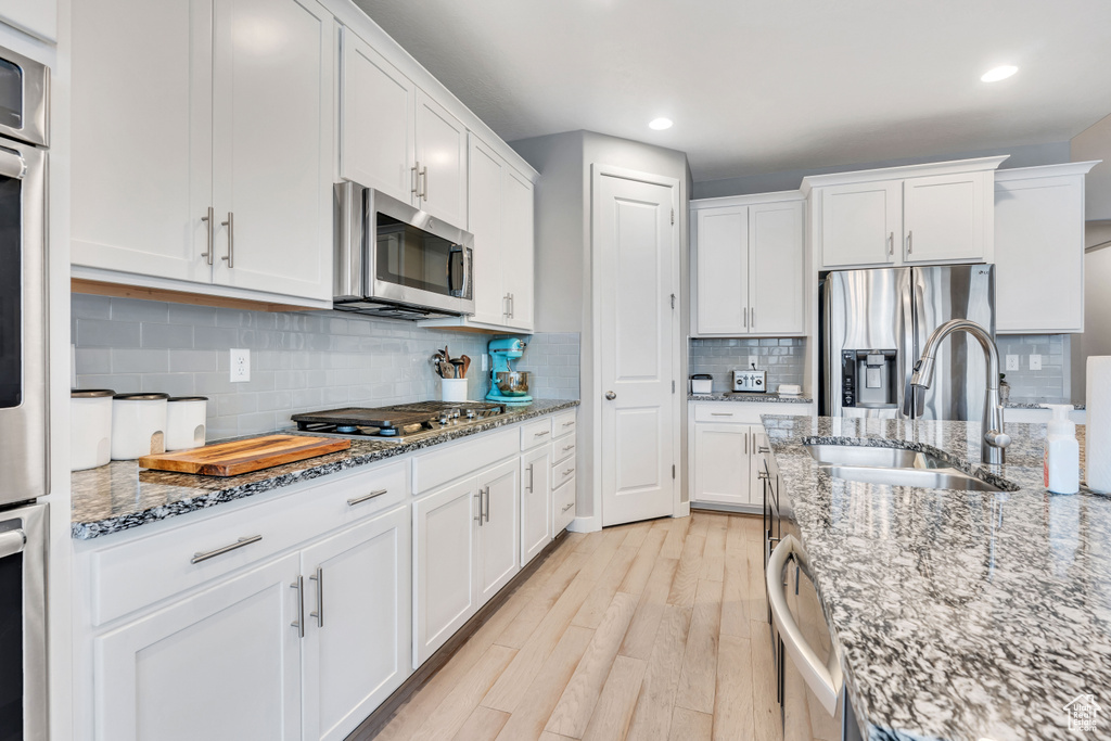 Kitchen featuring white cabinetry, stainless steel appliances, and backsplash