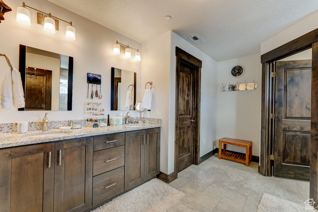 Bathroom featuring a textured ceiling, tile floors, large vanity, and double sink