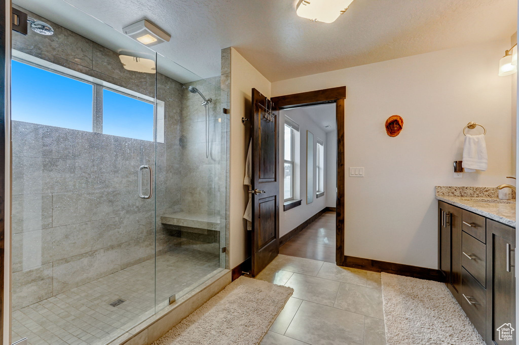 Bathroom featuring vanity, a textured ceiling, a shower with door, and tile floors