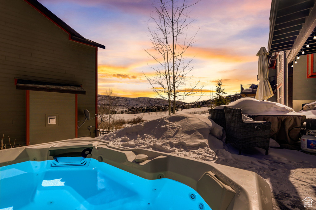 Snow covered pool with a mountain view and an outdoor hot tub