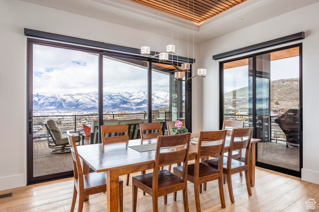 Dining area with a mountain view, light hardwood / wood-style floors, and a raised ceiling