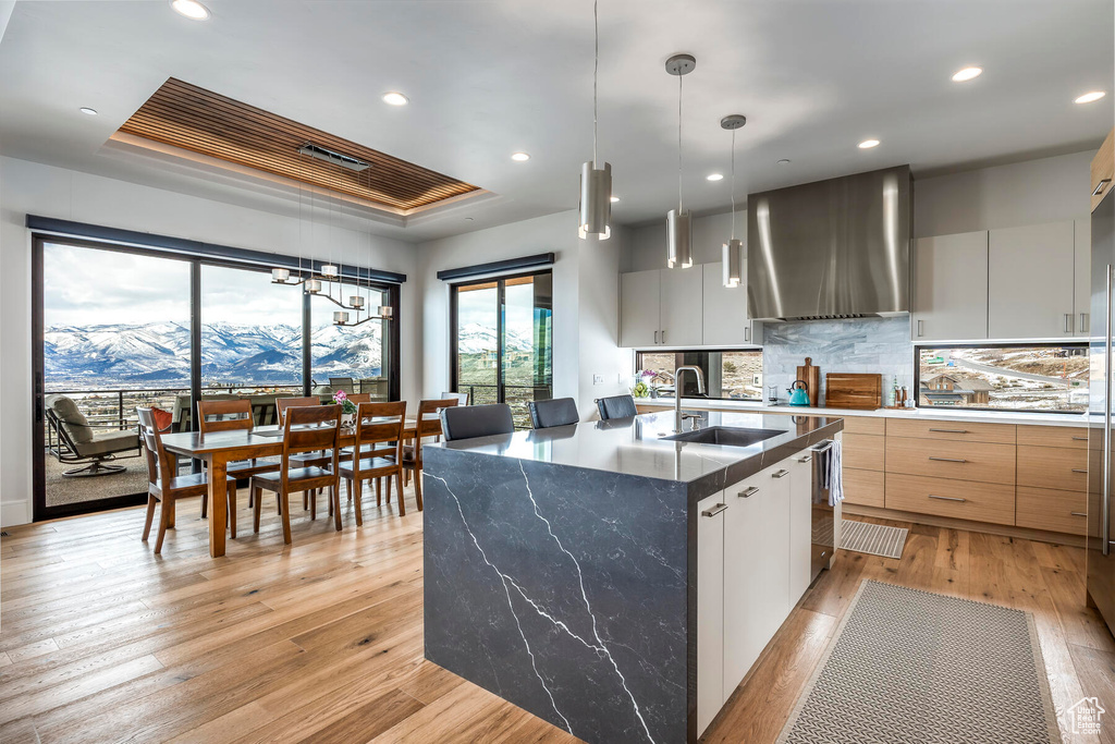 Kitchen featuring sink, wall chimney exhaust hood, a raised ceiling, hanging light fixtures, and a mountain view