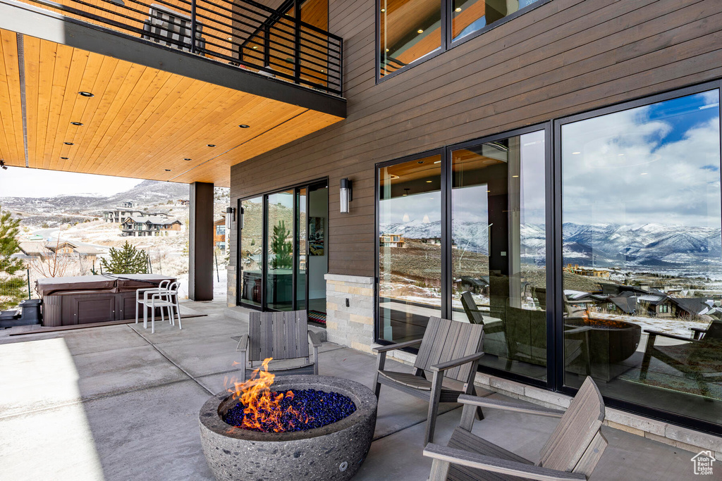 View of terrace with a hot tub, a mountain view, an outdoor fire pit, and a balcony