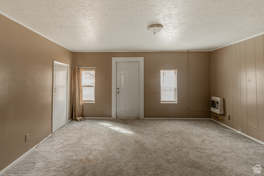 Empty room featuring a textured ceiling, light carpet, and an AC wall unit