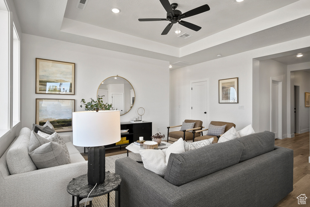 Living room featuring a raised ceiling, dark hardwood / wood-style flooring, and ceiling fan