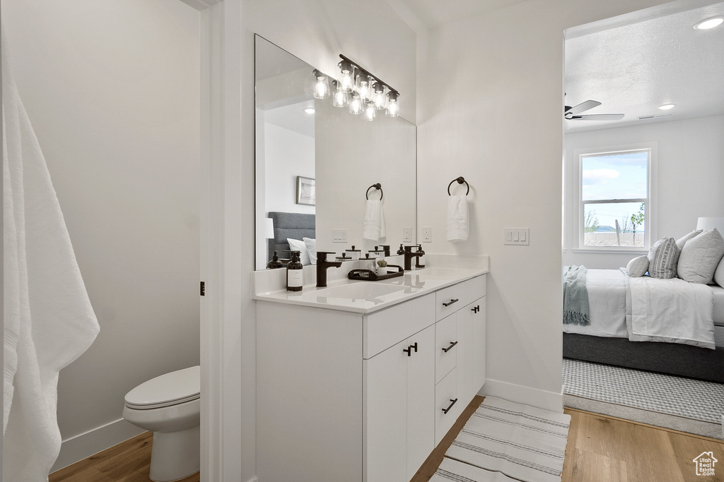 Bathroom featuring hardwood / wood-style flooring, large vanity, toilet, and ceiling fan