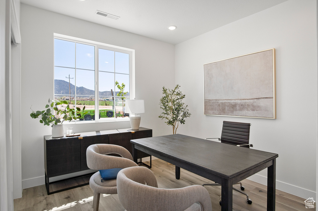 Office area featuring light wood-type flooring, a mountain view, and a healthy amount of sunlight