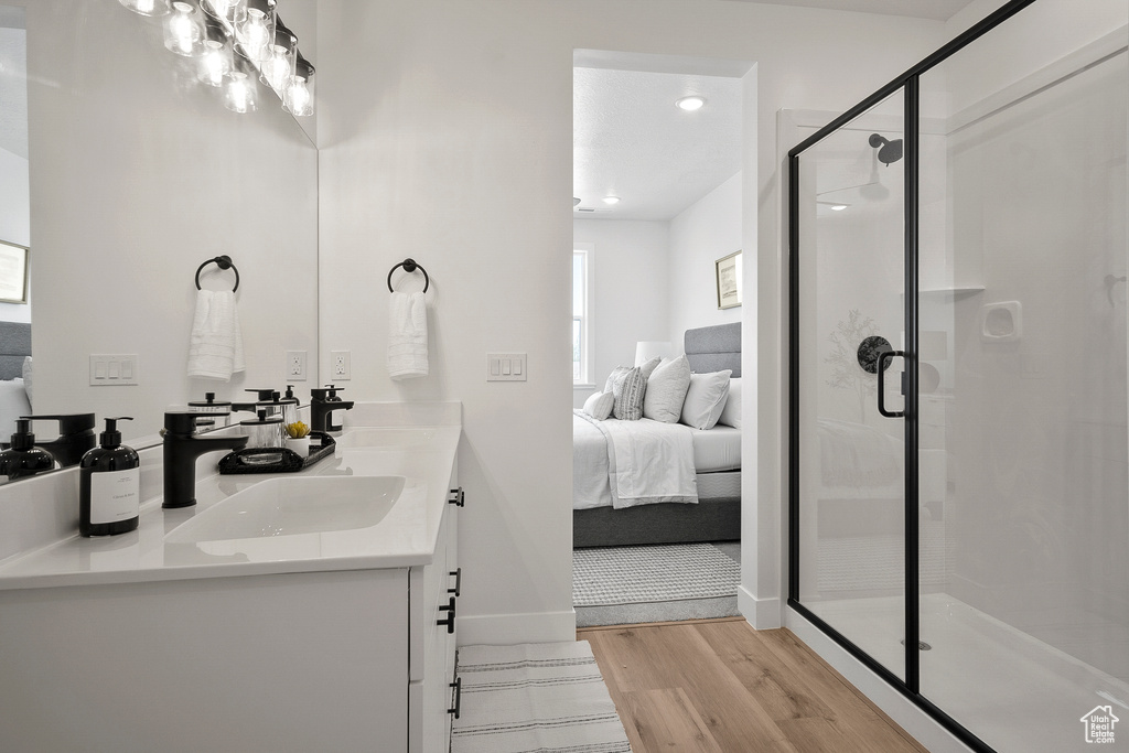 Bathroom featuring walk in shower, double sink, hardwood / wood-style flooring, and large vanity