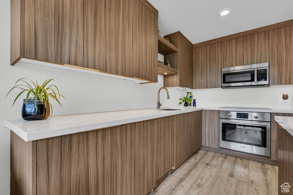 Kitchen featuring stainless steel appliances, light hardwood / wood-style floors, and sink