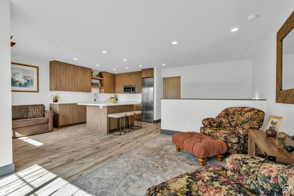 Kitchen with appliances with stainless steel finishes, light wood-type flooring, sink, and a kitchen breakfast bar