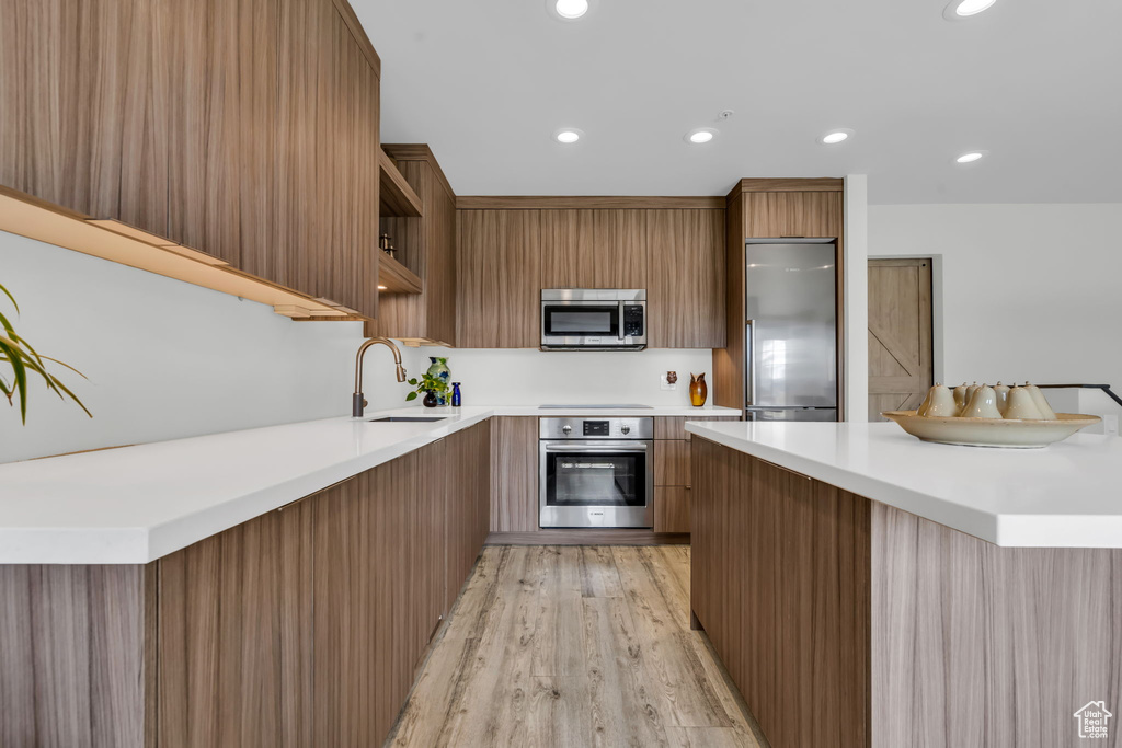 Kitchen with stainless steel appliances, sink, and light wood-type flooring