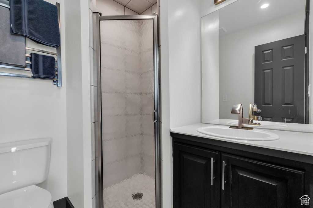 Bathroom featuring vanity, toilet, and a shower with door