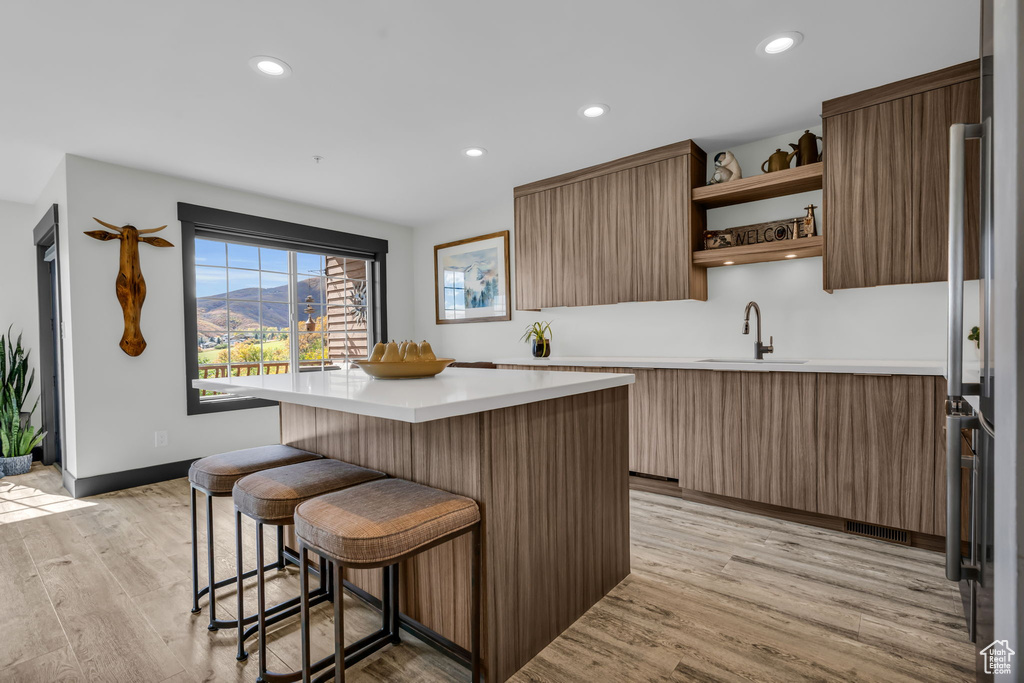 Kitchen featuring a kitchen island, light hardwood / wood-style flooring, a breakfast bar, and sink