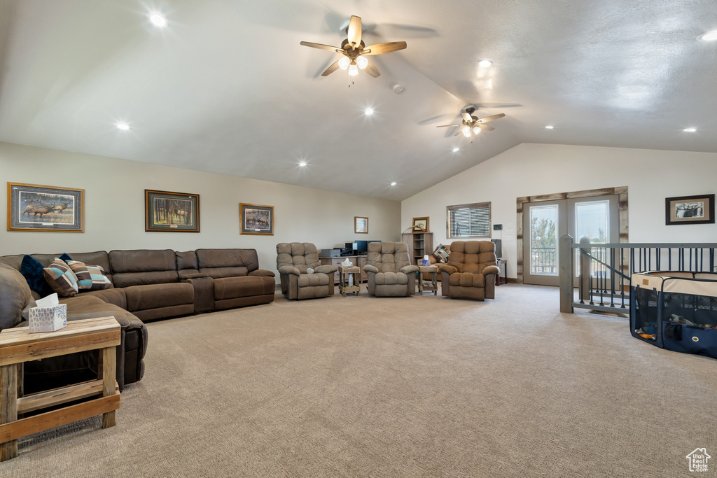 Carpeted living room with french doors, vaulted ceiling, and ceiling fan