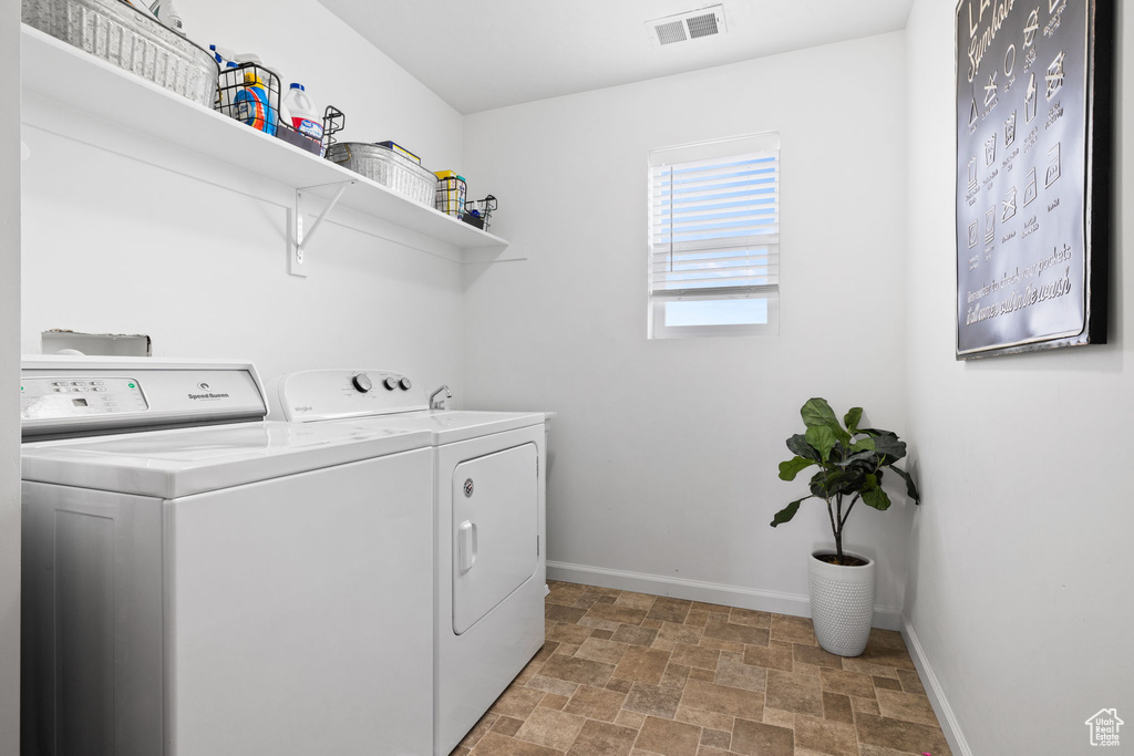 Clothes washing area featuring light tile floors and washer and clothes dryer