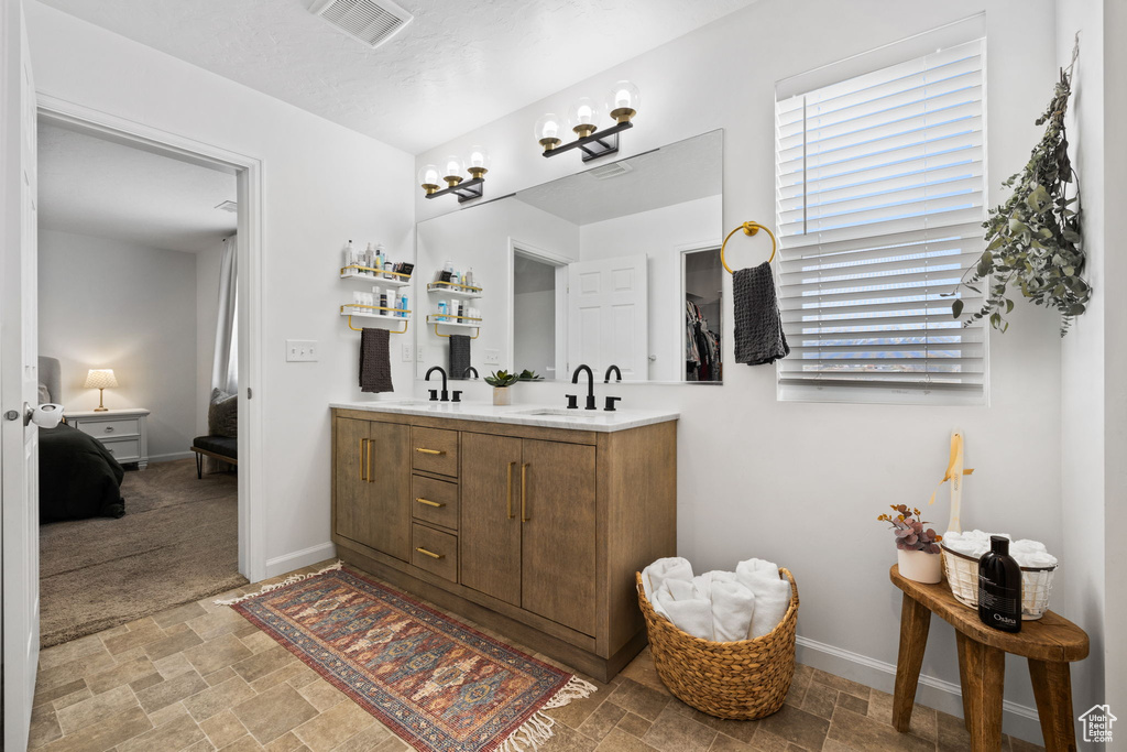 Bathroom featuring a chandelier, oversized vanity, tile floors, and dual sinks