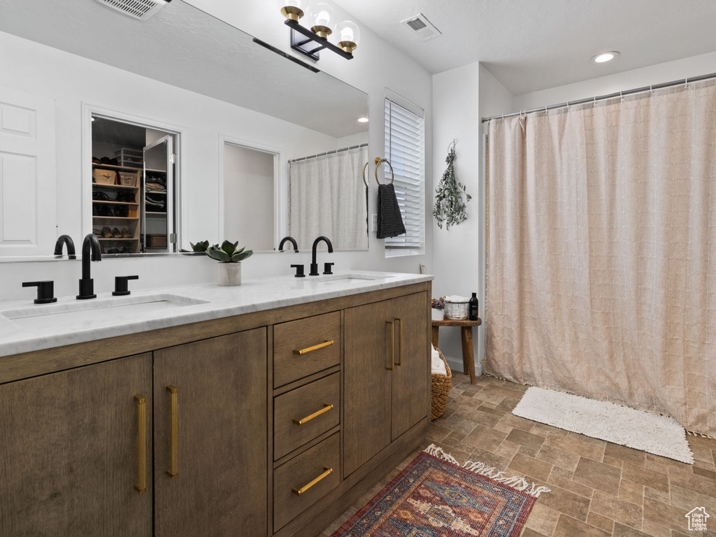 Bathroom with double sink, oversized vanity, an inviting chandelier, and tile flooring
