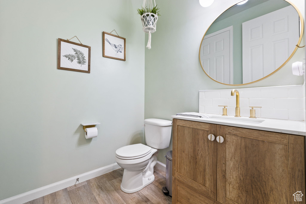 Bathroom featuring tasteful backsplash, hardwood / wood-style floors, toilet, and vanity