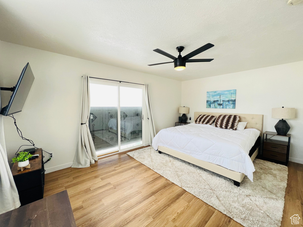 Bedroom with light wood-type flooring, access to outside, and ceiling fan
