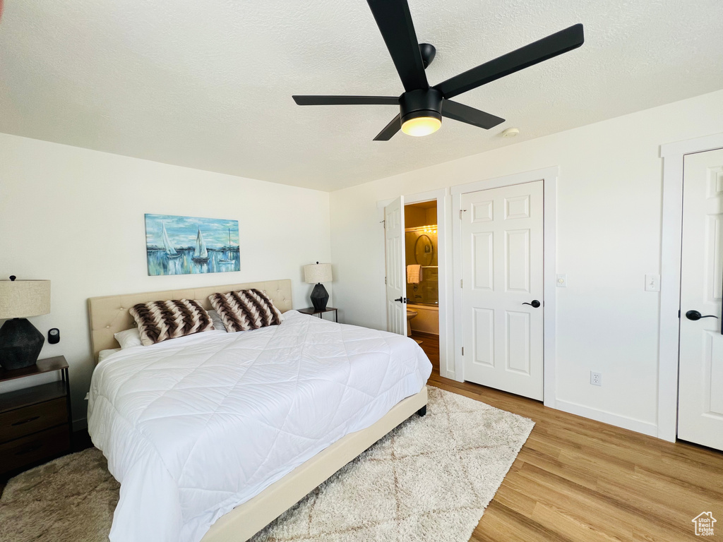 Bedroom with ensuite bath, ceiling fan, and light hardwood / wood-style flooring