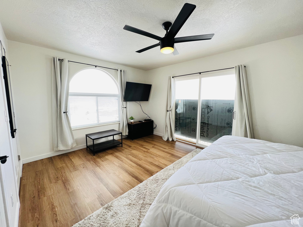 Bedroom featuring light hardwood / wood-style flooring, a textured ceiling, access to outside, and ceiling fan