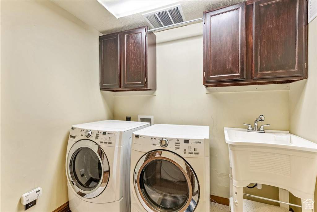 Clothes washing area with cabinets, hookup for a washing machine, and washer and dryer